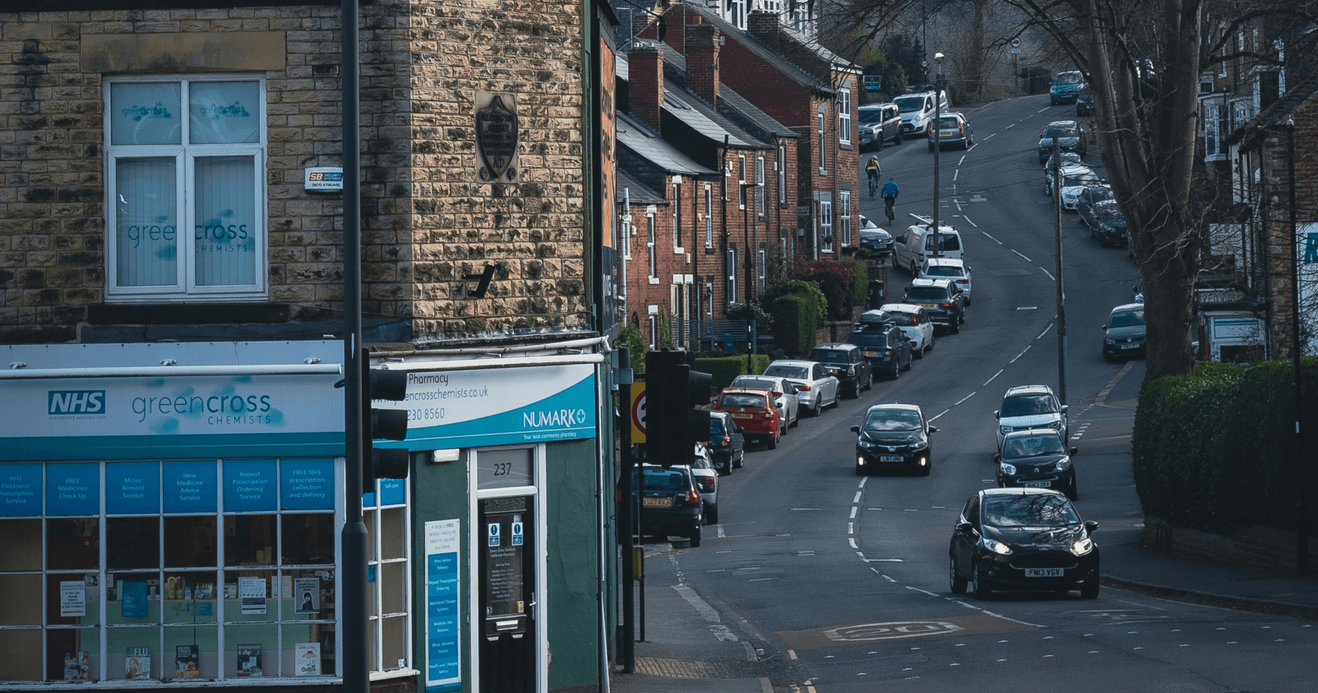 Winding uphill road and UK houses with a pharmacy in the foreground